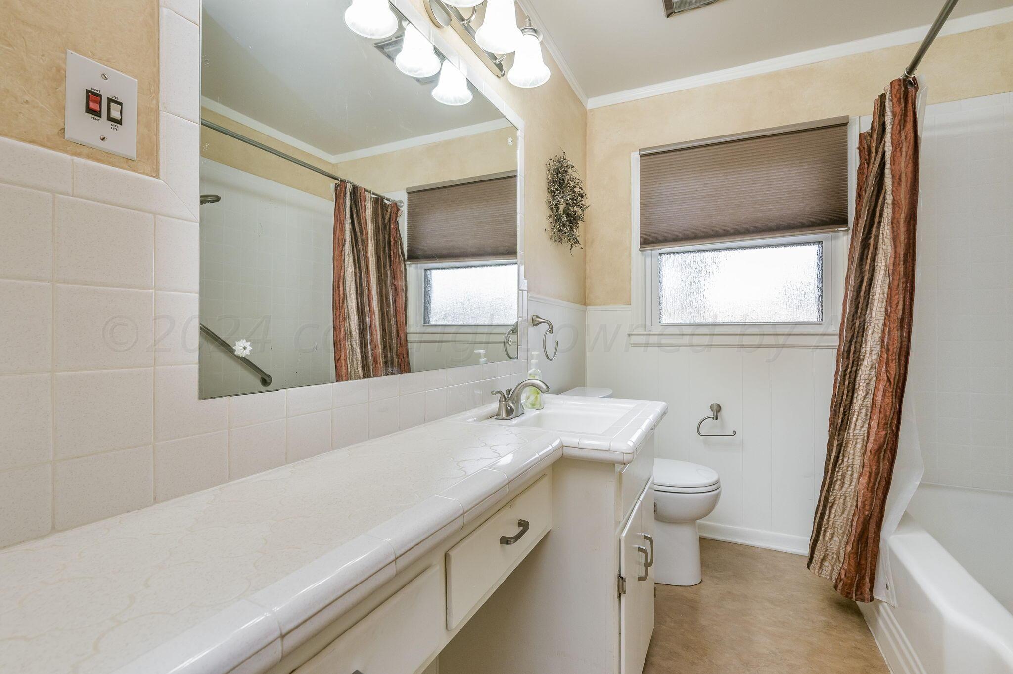 3415 Paramount Boulevard Amarillo, TX 79109 - Photo 25 of 44 a bathroom with a sink a toilet a mirror and window