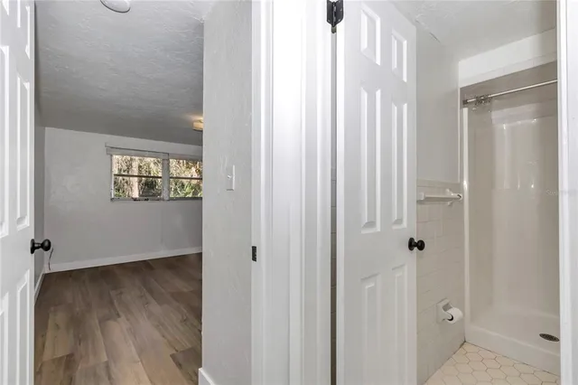a view of a hallway with wooden floor and a bathroom