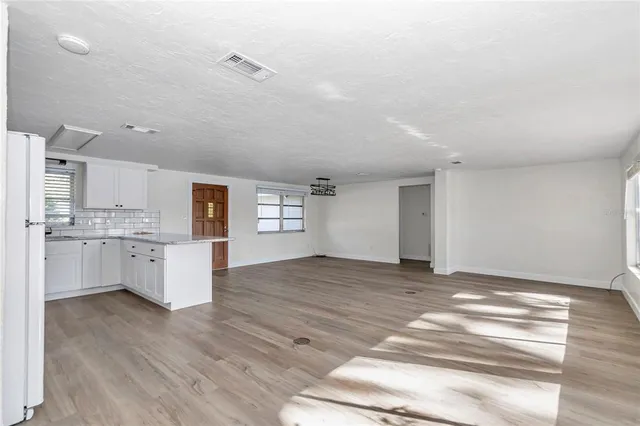 a view of a kitchen with wooden floor and a window