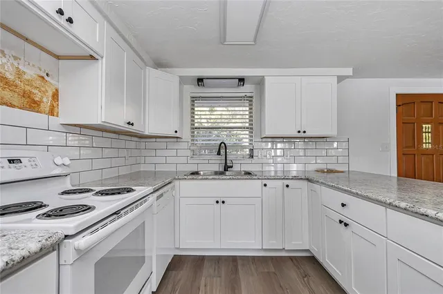 a kitchen with granite countertop a sink stove and cabinets