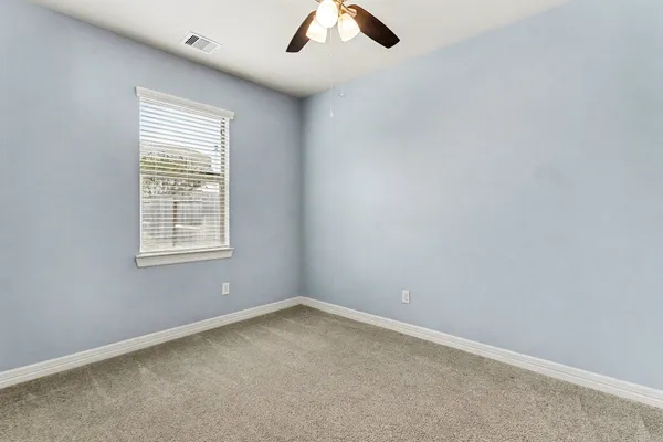 an empty room with ceiling fan and window