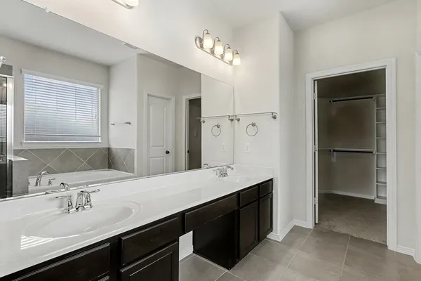 a spacious bathroom with a double vanity sink a mirror and shower