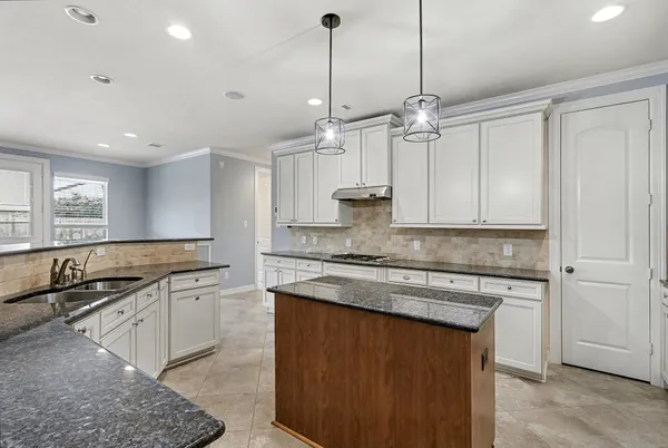 a kitchen with stainless steel appliances granite countertop a sink a stove a refrigerator and island with wooden floor