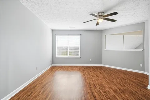 an empty room with wooden floor fan and windows