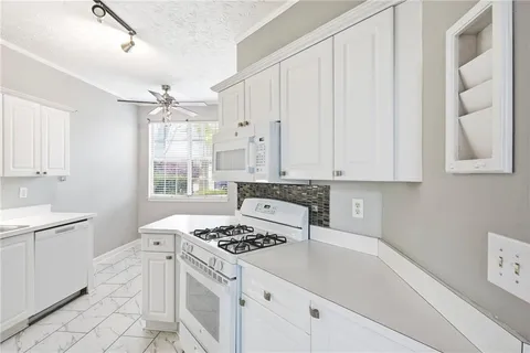 a kitchen with granite countertop a stove a sink dishwasher and white cabinets with wooden floor