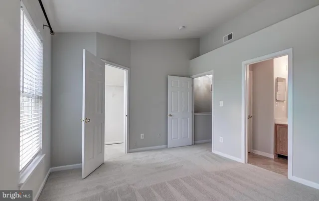 a view of an empty room with window and bathroom