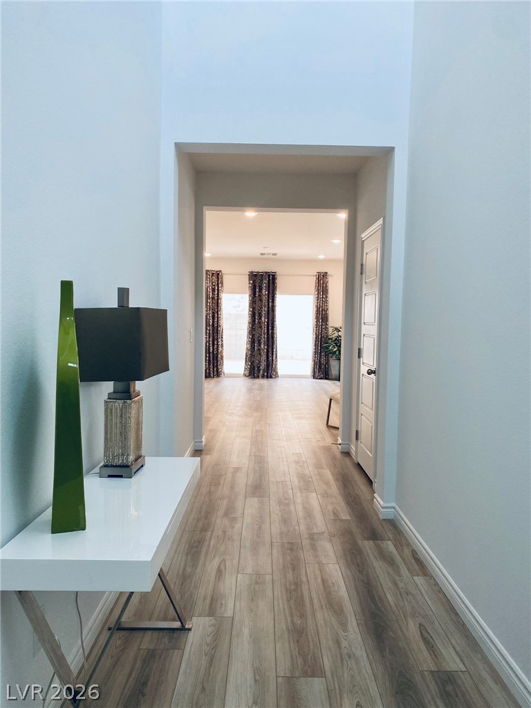 4457 Sawyer Ridge Street Las Vegas, NV 89147 - Photo 7 of 32 An inviting hallway with wood flooring leads to a spacious room, bathed in natural light.