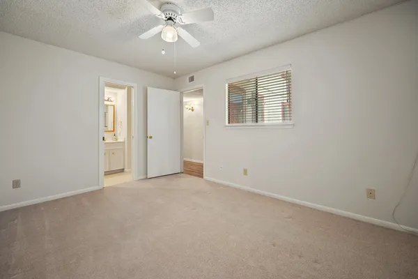 an empty room with a chandelier fan and windows