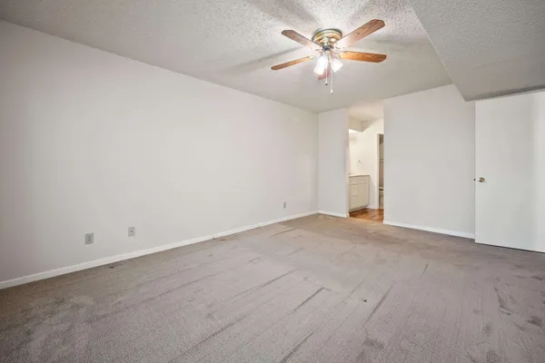 an empty room with chandelier fan and window