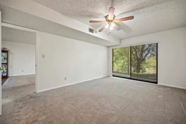 an empty room with windows and fan