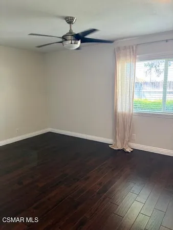 an empty room with wooden floor fan and windows