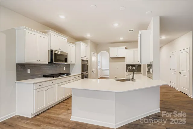 a kitchen with a sink cabinets wooden floor and stainless steel appliances
