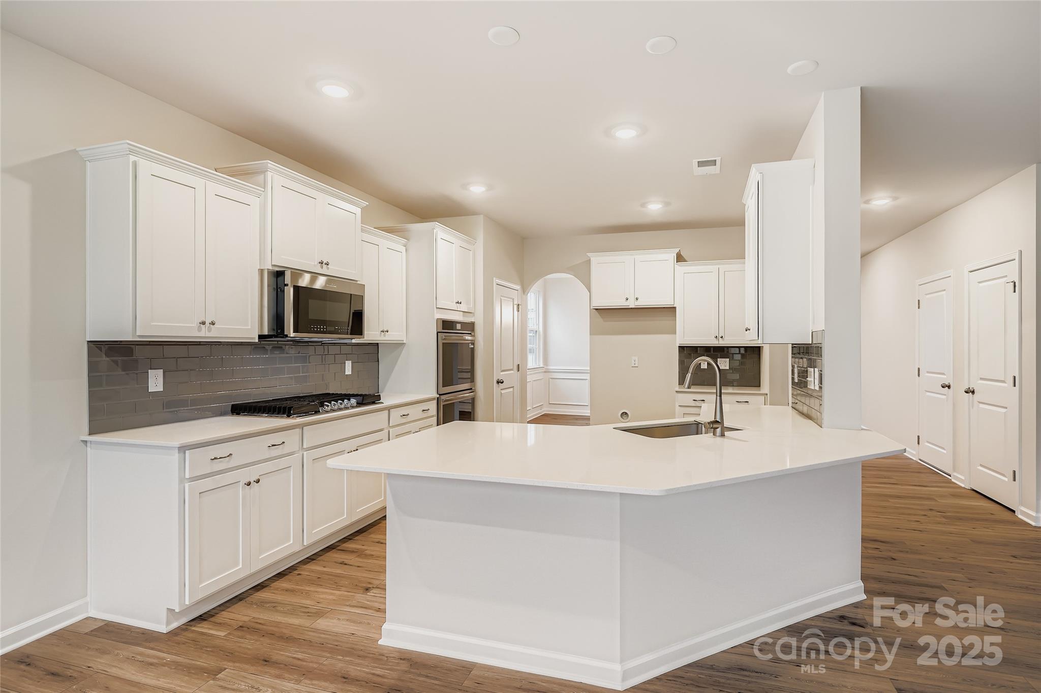 4356 Shimmering Stone Way Maiden, NC 28650 - Photo 4 of 13 a kitchen with stainless steel appliances a stove top oven a sink a refrigerator white cabinets and wooden floor