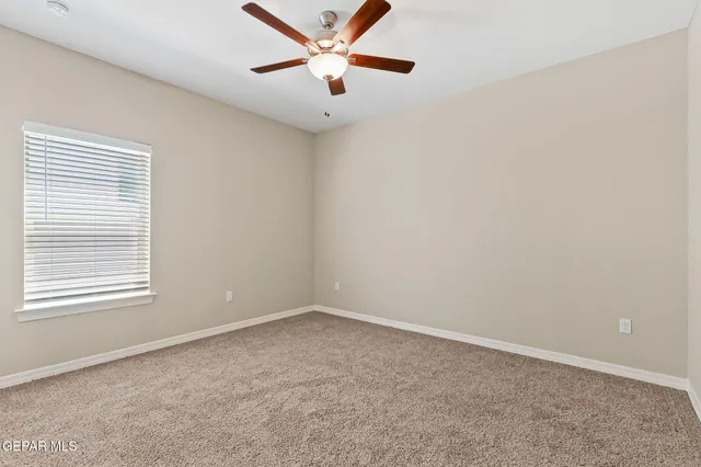 an empty room with a window and a fan