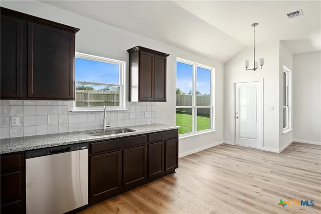 a large white kitchen with a sink and dishwasher a stove top oven with wooden floor