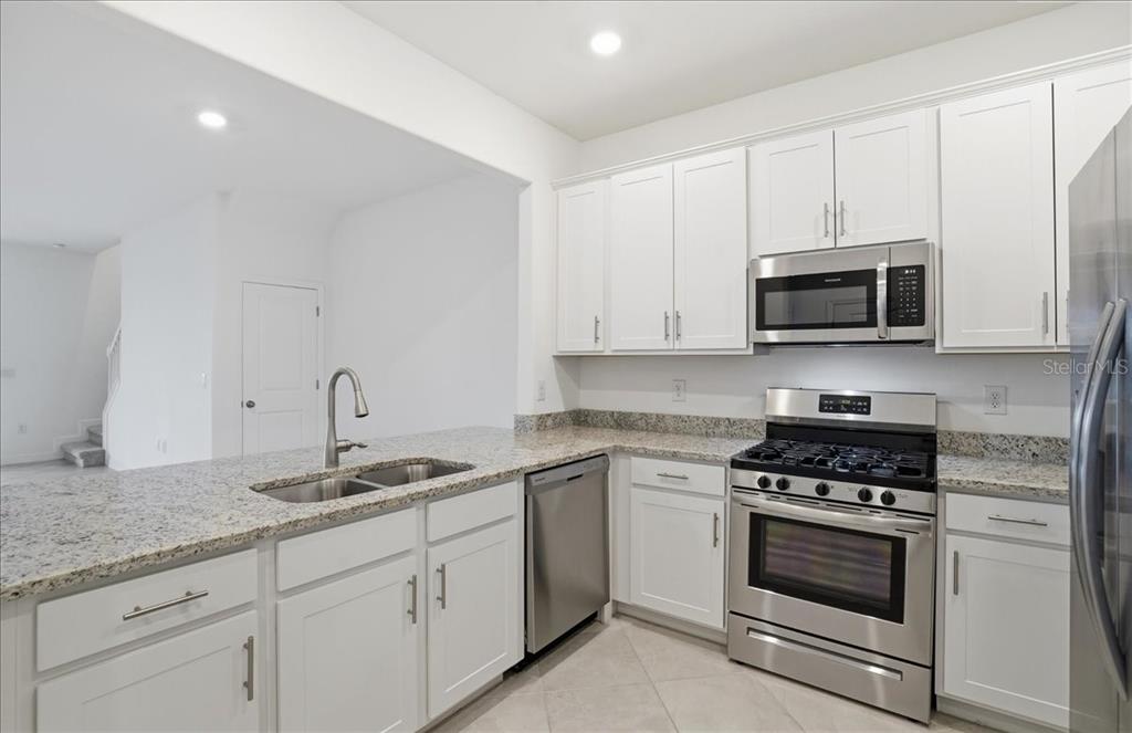 14740 Lyla Terrace Lakewood Ranch, FL 34211 - Photo 11 of 68 a kitchen with granite countertop white cabinets and stainless steel appliances