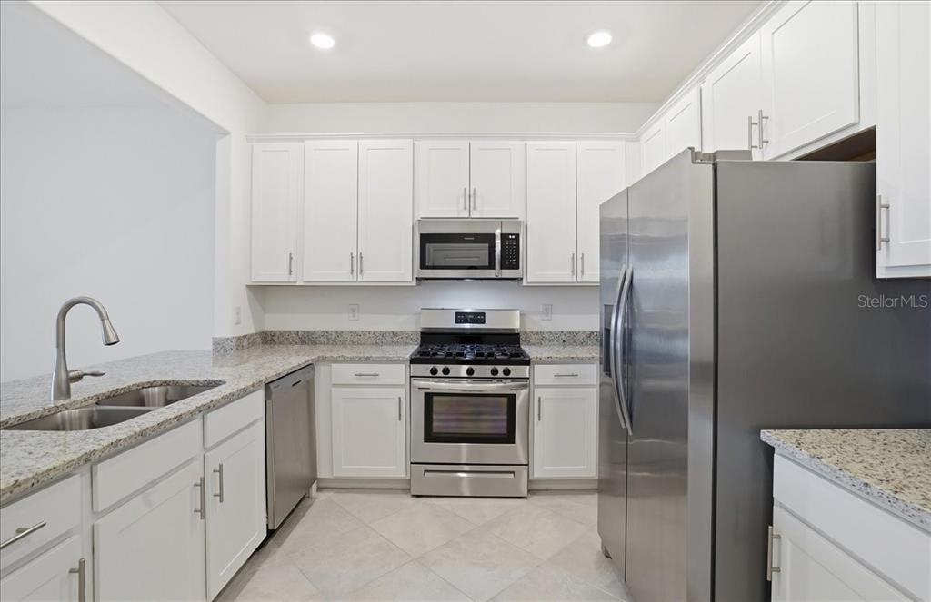 14740 Lyla Terrace Lakewood Ranch, FL 34211 - Photo 12 of 68 a kitchen with stainless steel appliances granite countertop a stove a refrigerator and a sink