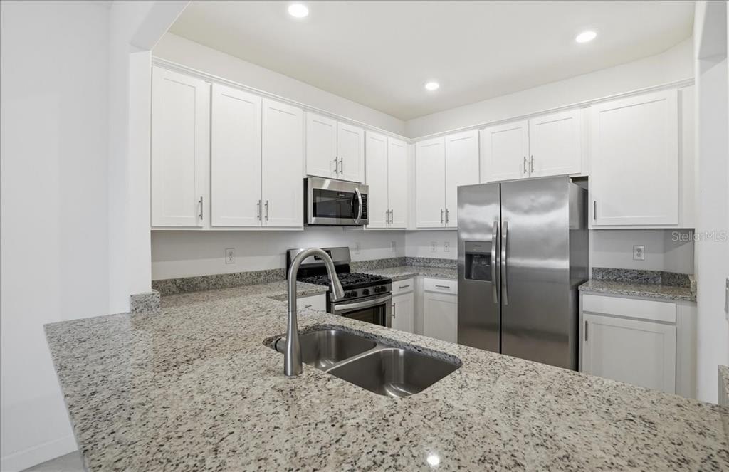 14740 Lyla Terrace Lakewood Ranch, FL 34211 - Photo 13 of 68 a kitchen with granite countertop a refrigerator sink and microwave