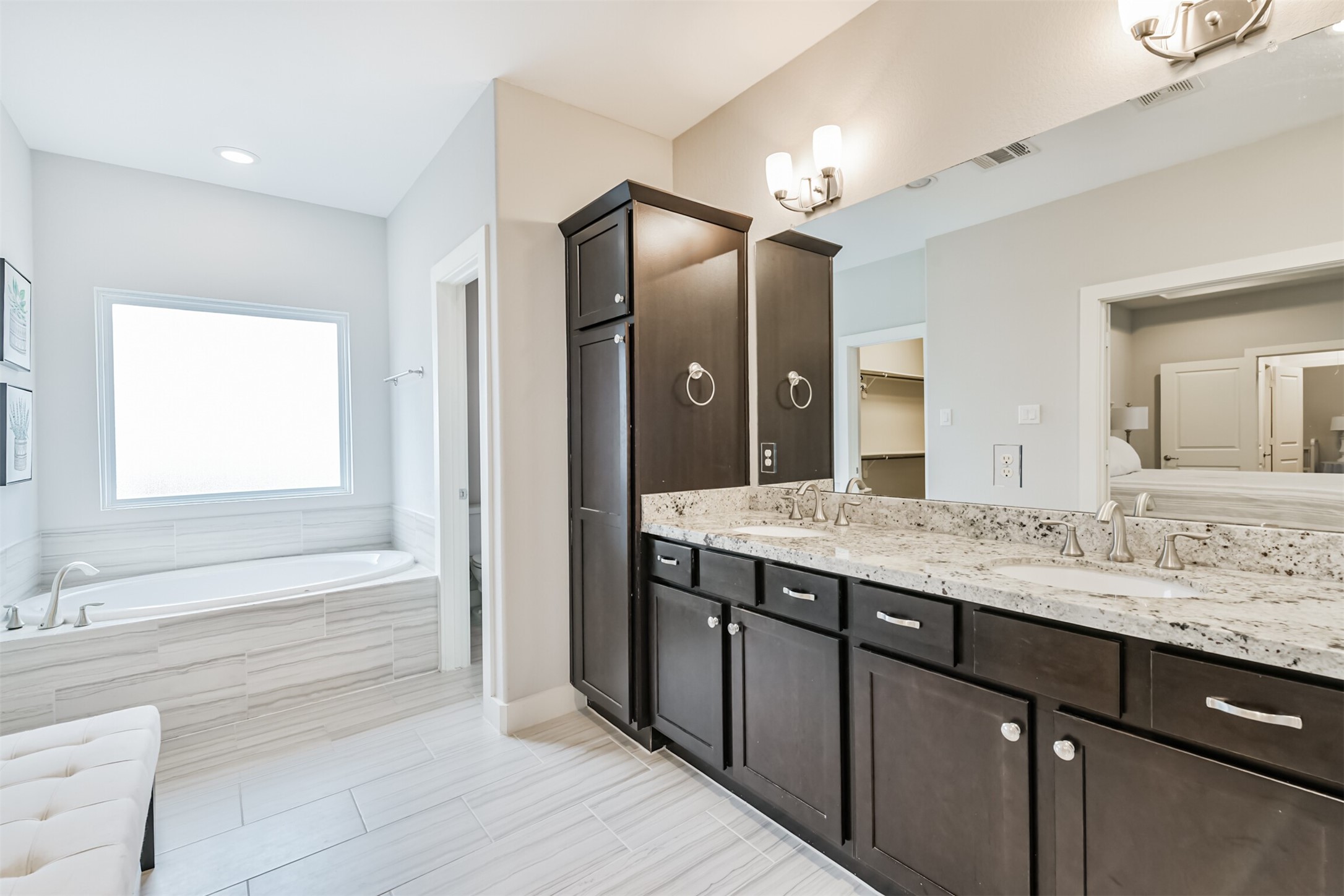 The primary bathroom features a soaking tub with a large frosted glass window, double sinks, separate water closet for the toilet, ample storage, and a grand walk in shower.