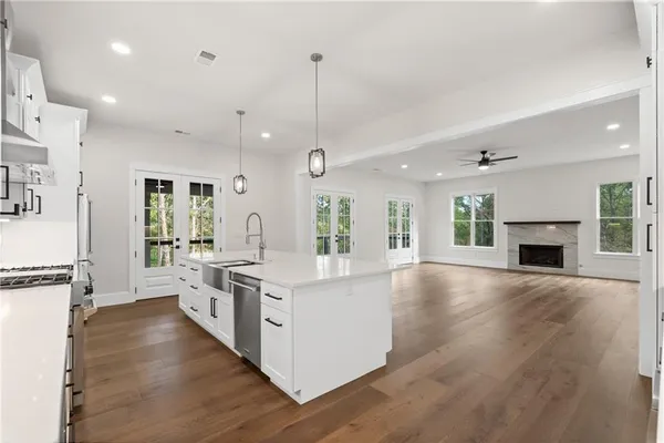 a large kitchen with kitchen island a stove a sink a refrigerator and a fireplace with wooden floor