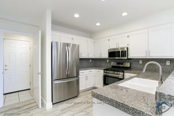 a kitchen with stainless steel appliances granite countertop a refrigerator stove microwave and sink