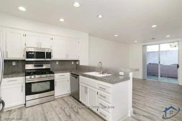 a kitchen with stainless steel appliances granite countertop a stove a sink and a microwave