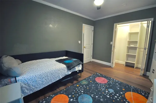 a bedroom with a bed and dresser with wooden floor