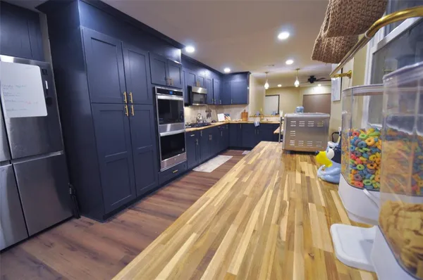 a large kitchen with stainless steel appliances kitchen island granite countertop a refrigerator and a stove