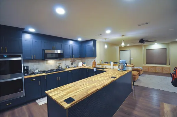 a large kitchen with kitchen island a sink stove and wooden cabinets
