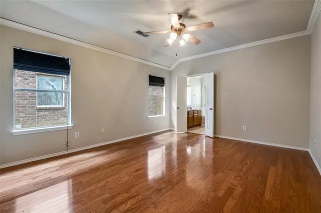 a view of an empty room with a window and wooden floor