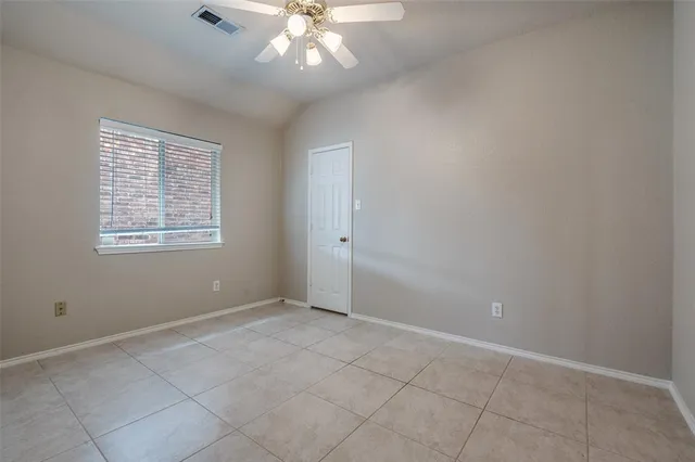 an empty room with chandelier fan and windows