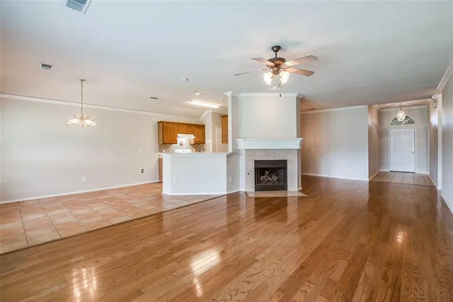 a view of a livingroom with a fireplace a ceiling fan and wooden floor