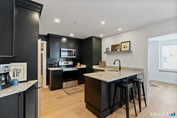 a kitchen with a sink a stove a refrigerator cabinets and a dining table