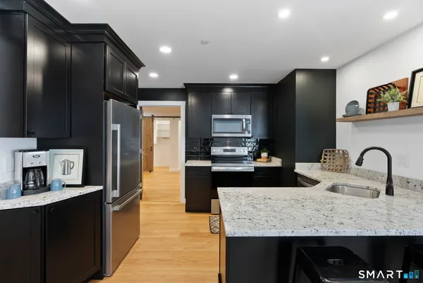 a large kitchen with granite countertop lots of counter space and stainless steel appliances