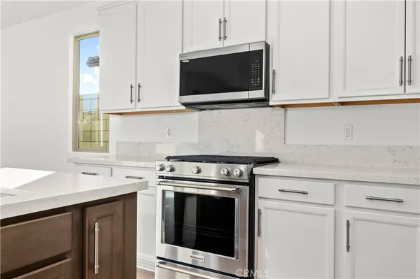 a kitchen with stainless steel appliances granite countertop white cabinets a sink and a stove
