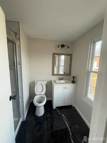 a bathroom with a granite countertop toilet sink and mirror