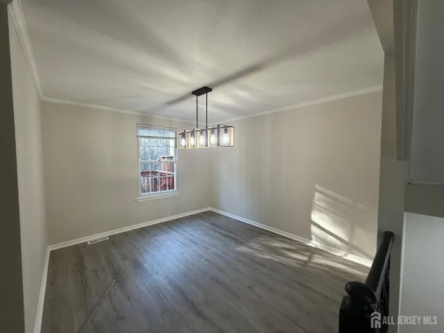 an empty room with wooden floor chandelier and windows