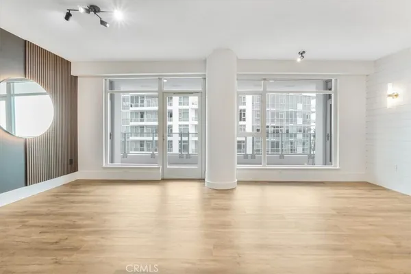 a view of an empty room with a window and wooden floor
