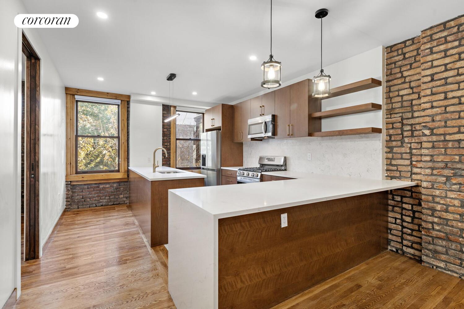 154 9th Avenue Manhattan, NY 10011 - Photo 6 of 11 a kitchen with stainless steel appliances a sink stove and wooden floor