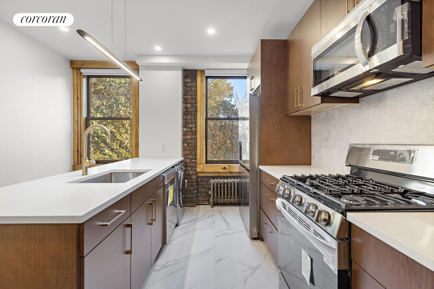 154 9th Avenue Manhattan, NY 10011 - Photo 7 of 11 a kitchen with stainless steel appliances granite countertop a stove and a sink