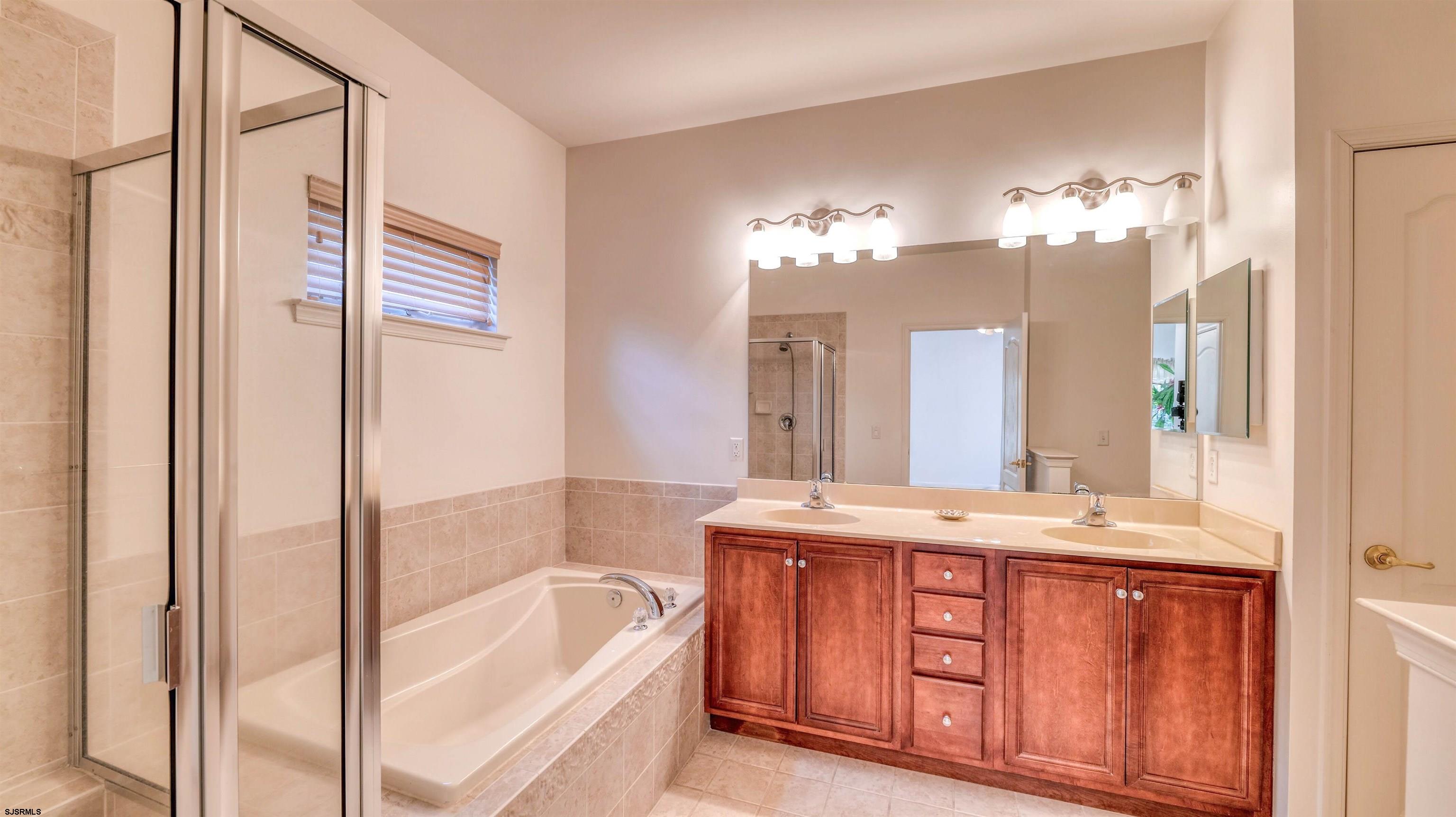 212 Lander Road Egg Harbor Township, NJ 08234 - Photo 17 of 33 a bathroom with a tub a double vanity sink and a mirror