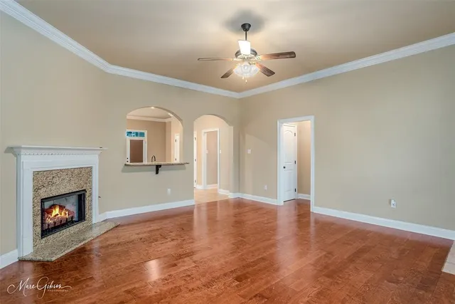 a view of an empty room with chandelier fan and fire place