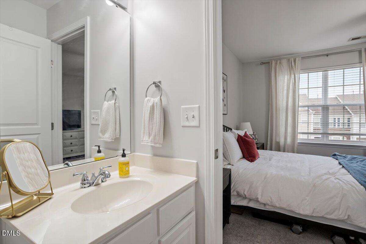 5349 Silver Moon Lane Raleigh, NC 27606 - Photo 25 of 41 a bedroom with a bed a mirror and a sink