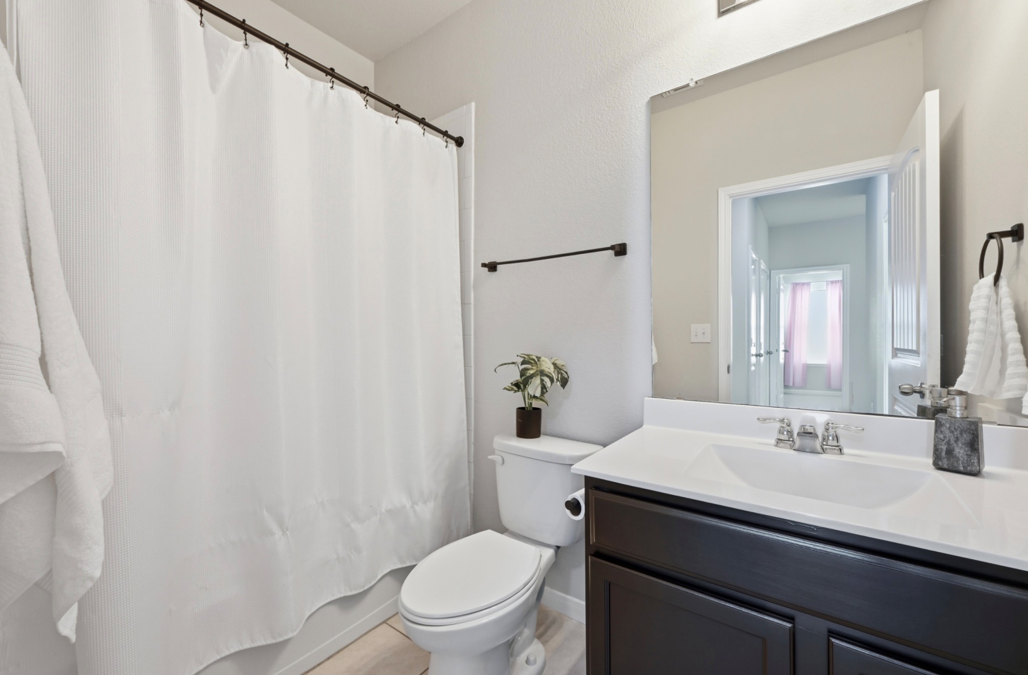 9716 Baden Lane Austin, TX 78754 - Photo 24 of 30 a bathroom with a sink a toilet a mirror and shower curtain