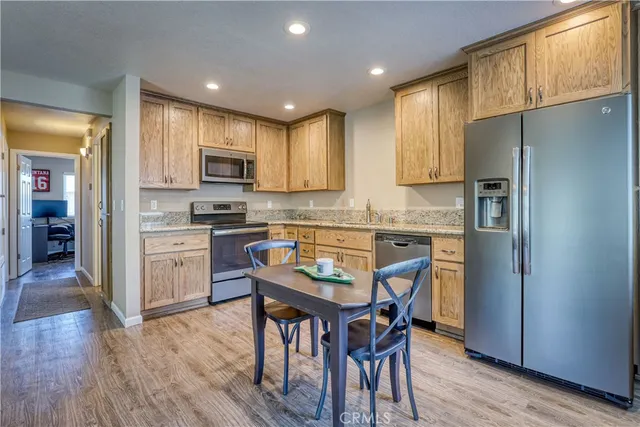 a kitchen with stainless steel appliances granite countertop a refrigerator a sink a stove a dining table and chairs