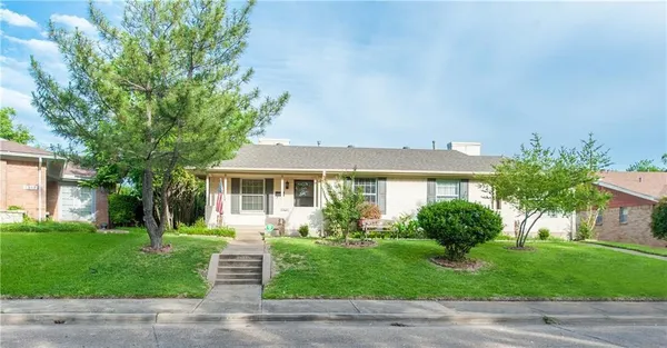 a front view of a house with a garden and trees
