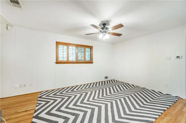 a view of a livingroom with a fireplace a ceiling fan and wooden floor