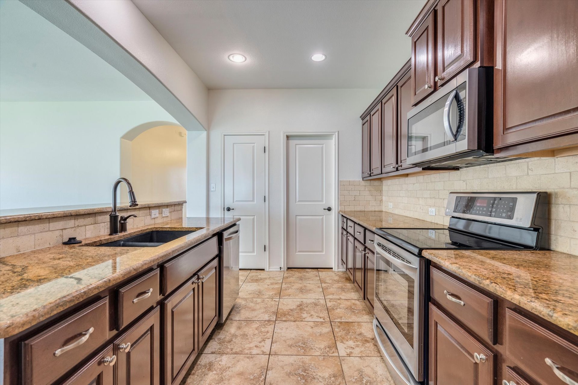 16829 Ruggio Road Pflugerville, TX 78660 - Photo 13 of 40 a kitchen with stainless steel appliances granite countertop a sink stove and cabinets