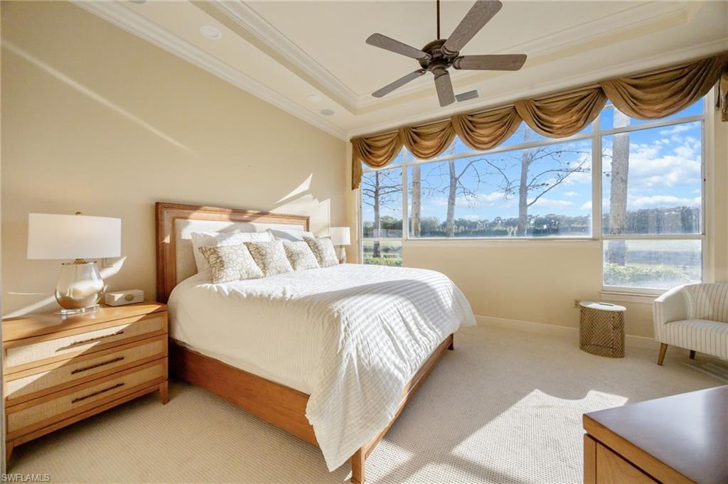 15532 Monterosso Lane, Unit 102 Naples, FL 34110 - Photo 24 of 49 a bedroom with a bed a dresser and a chandelier