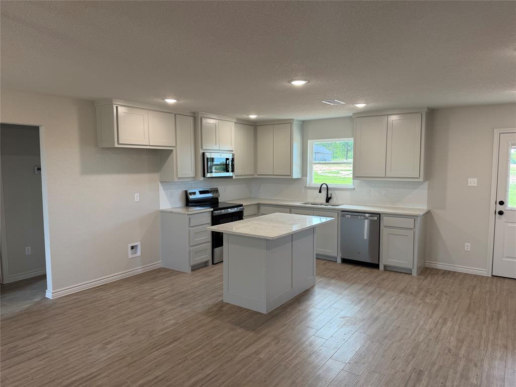2998 Knob Road Springtown, TX 76082 - Photo 2 of 7 a kitchen with stainless steel appliances granite countertop a sink a stove a refrigerator cabinets and a wooden floor